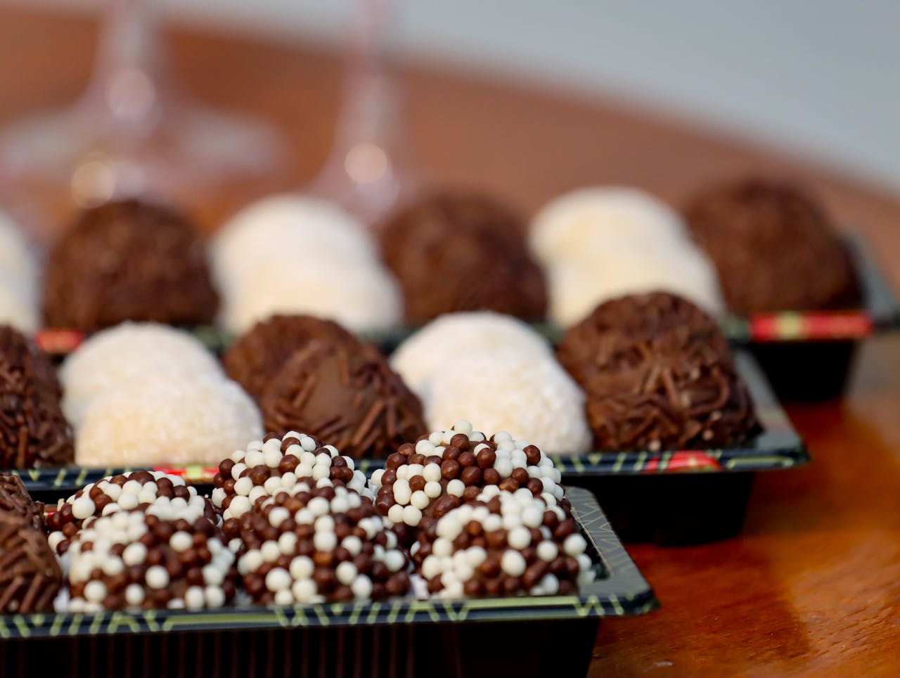 An assortment of sweet Brazilian brigadeiros in various flavors displayed on a wooden table.